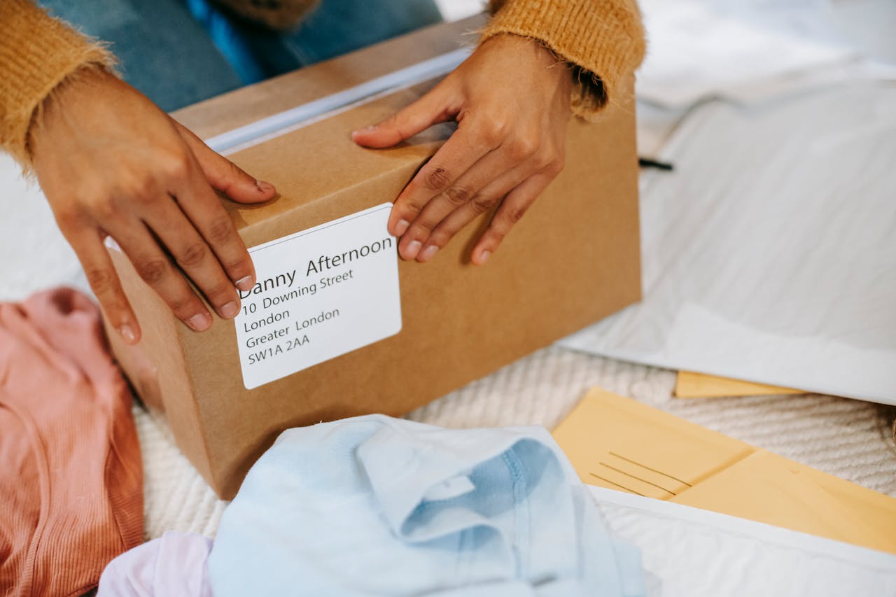 Close-up of hands preparing a cardboard package for shipping indoors.